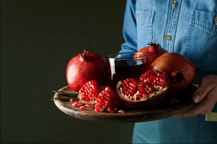 Woman holding pomegranate tray — dietary strategies alongside supplementation produce the best Akkermansia outcomes